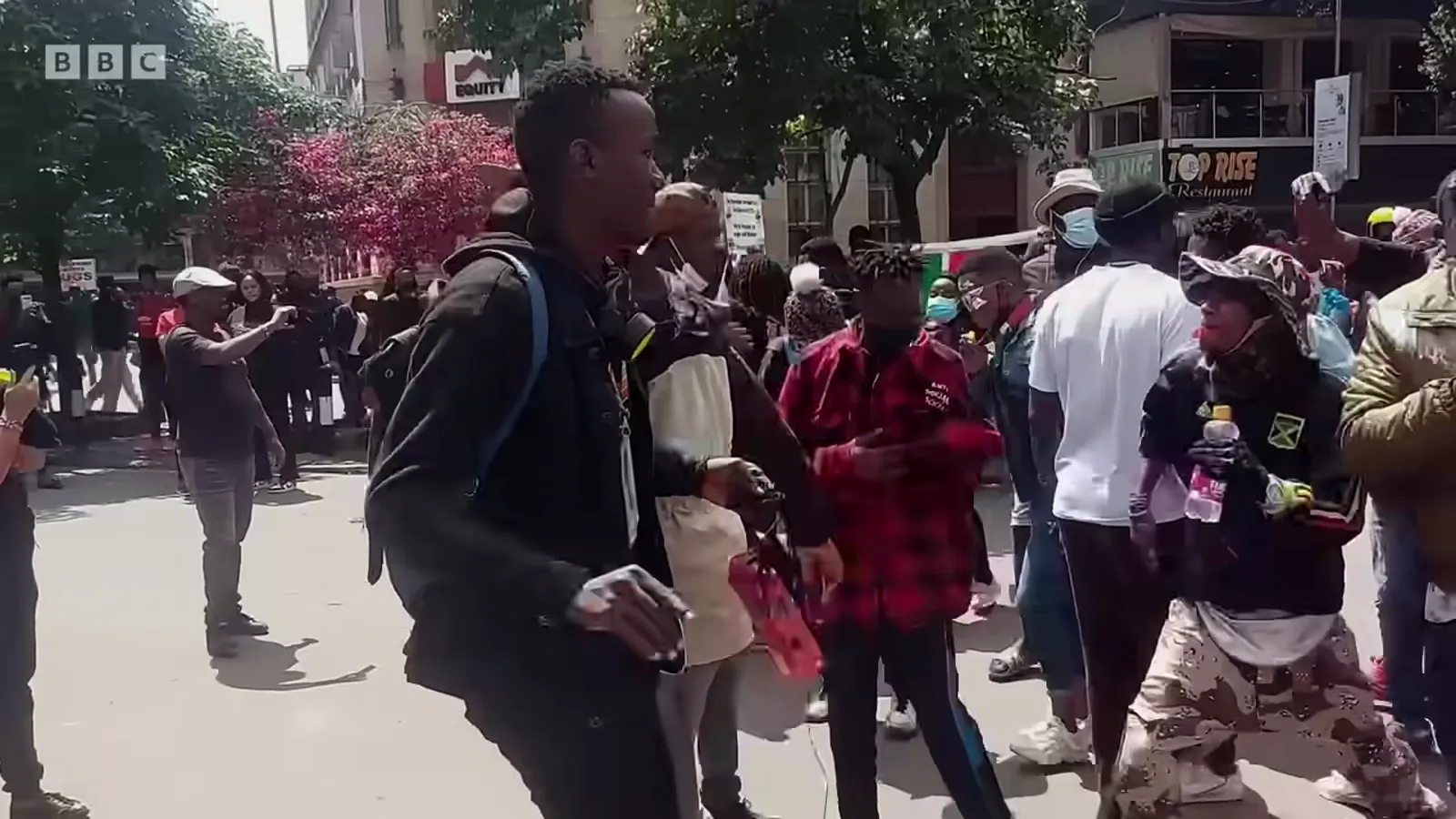Protesters march through central Nairobi holding a large Kenyan flag.