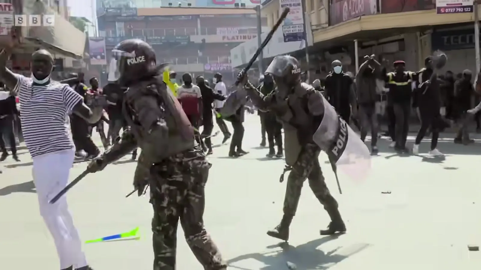 Riot police with batons charge protesters on a Nairobi street.