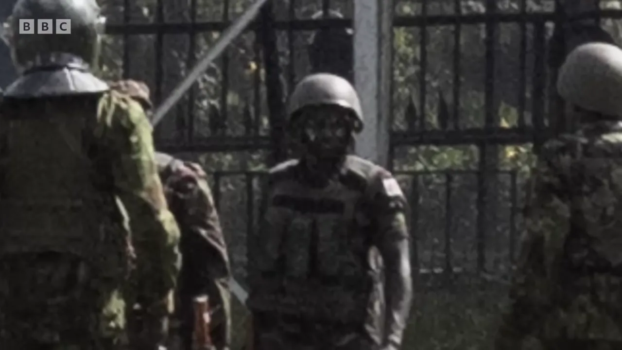A soldier in a matte green helmet and body armour stands at the parliament gate, minutes after the shooting.